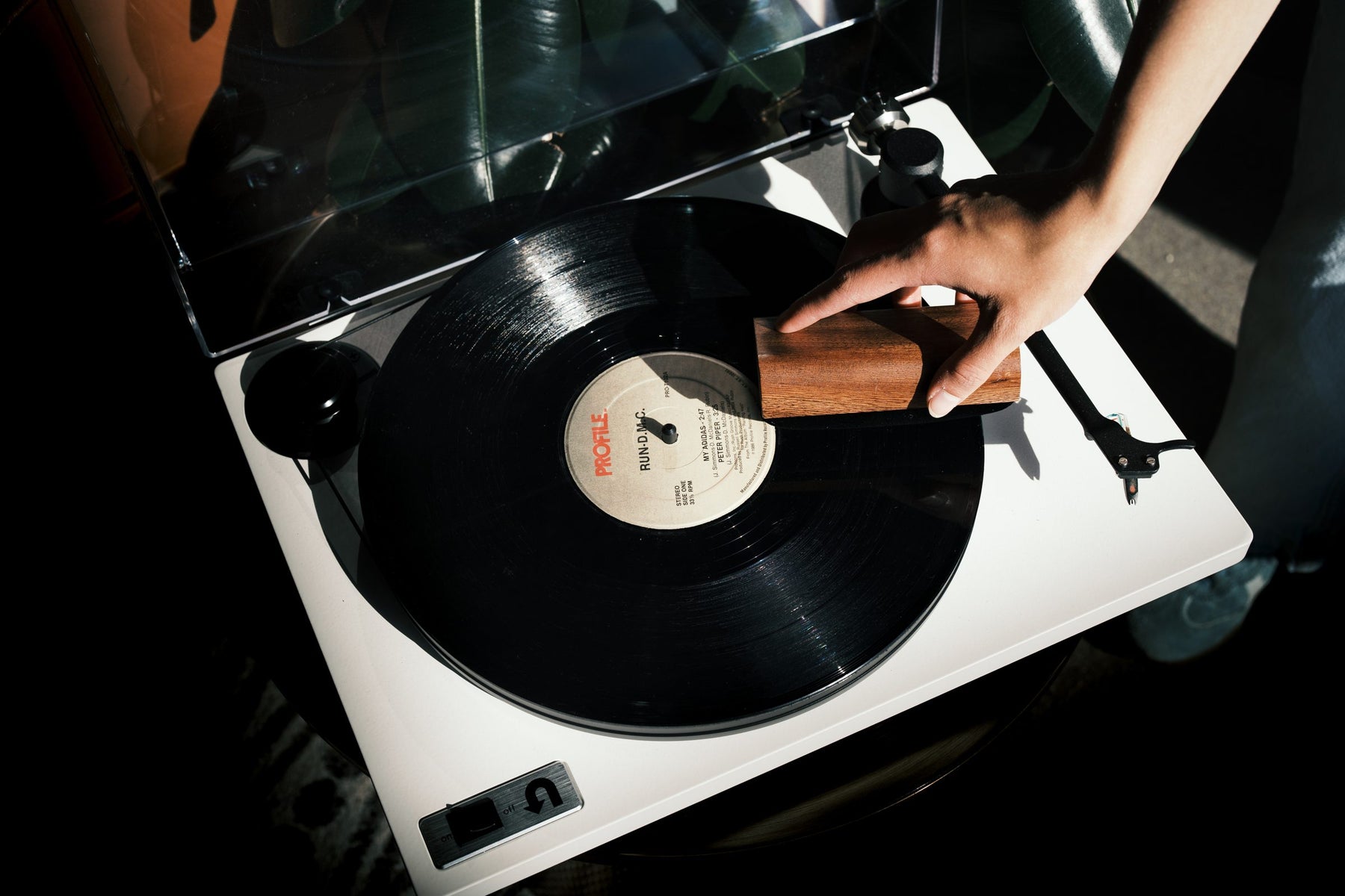 Hand sweeping a Vinylbuddy velvet brush across a spinning record on a white turntable