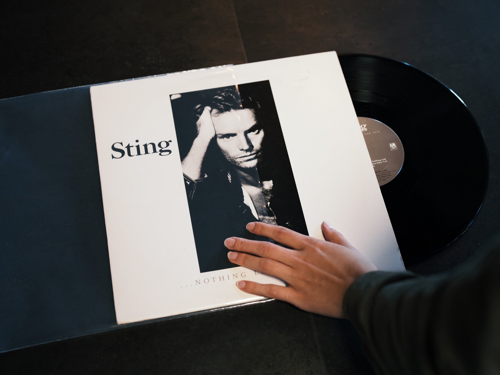 Hand sliding a record jacket into a Vinyl Buddy crystal clear outer sleeve